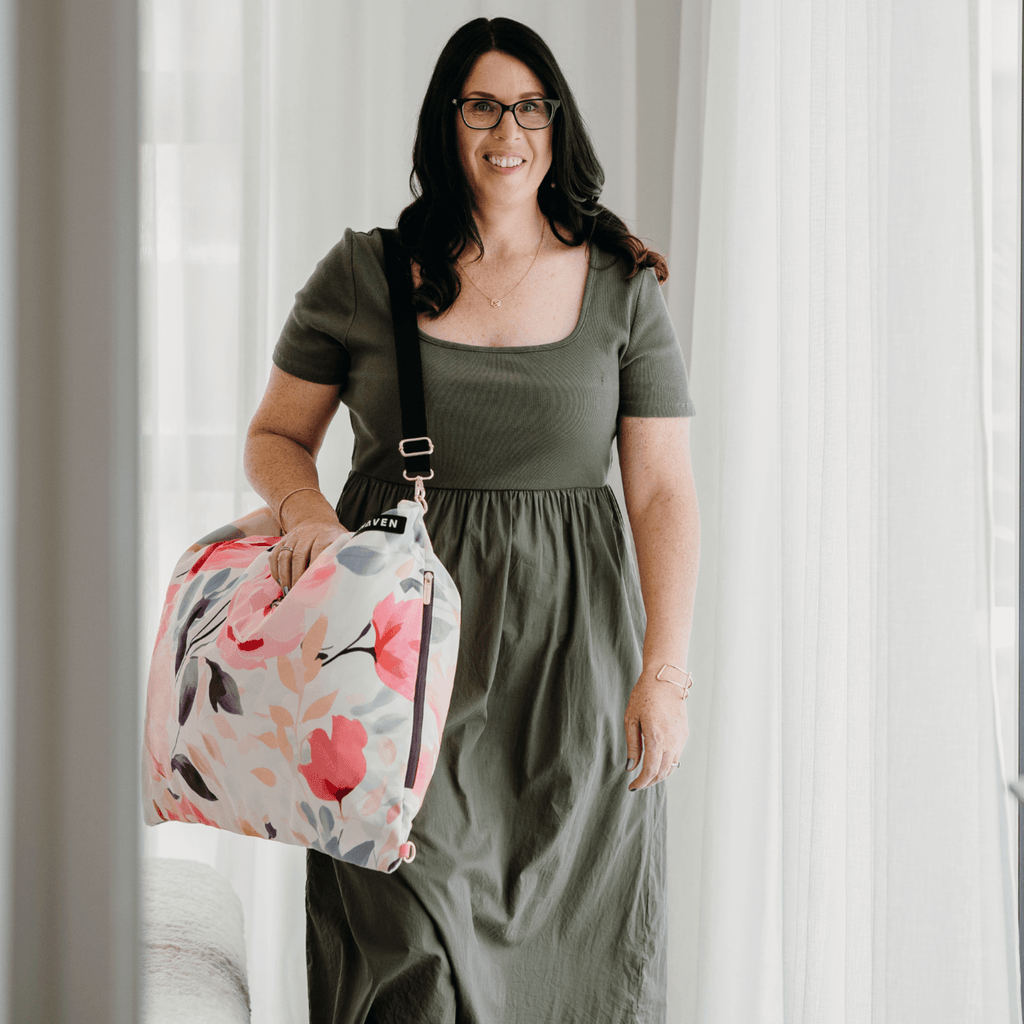 Dream First™ Pillow Bag - Flora - Solhaven carried by a brunette woman on a hotel room with sheer curtains