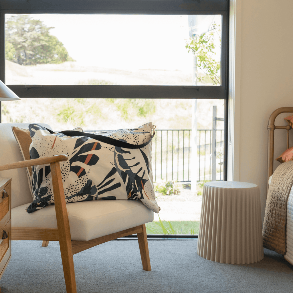 Dream First™ Pillow Bag - Tropic - Solhaven shown sitting on a chair in an Airbnb bedroom